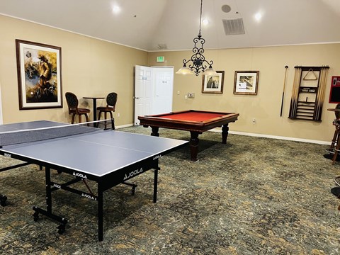 a game room with two ping pong tables and a red pool table