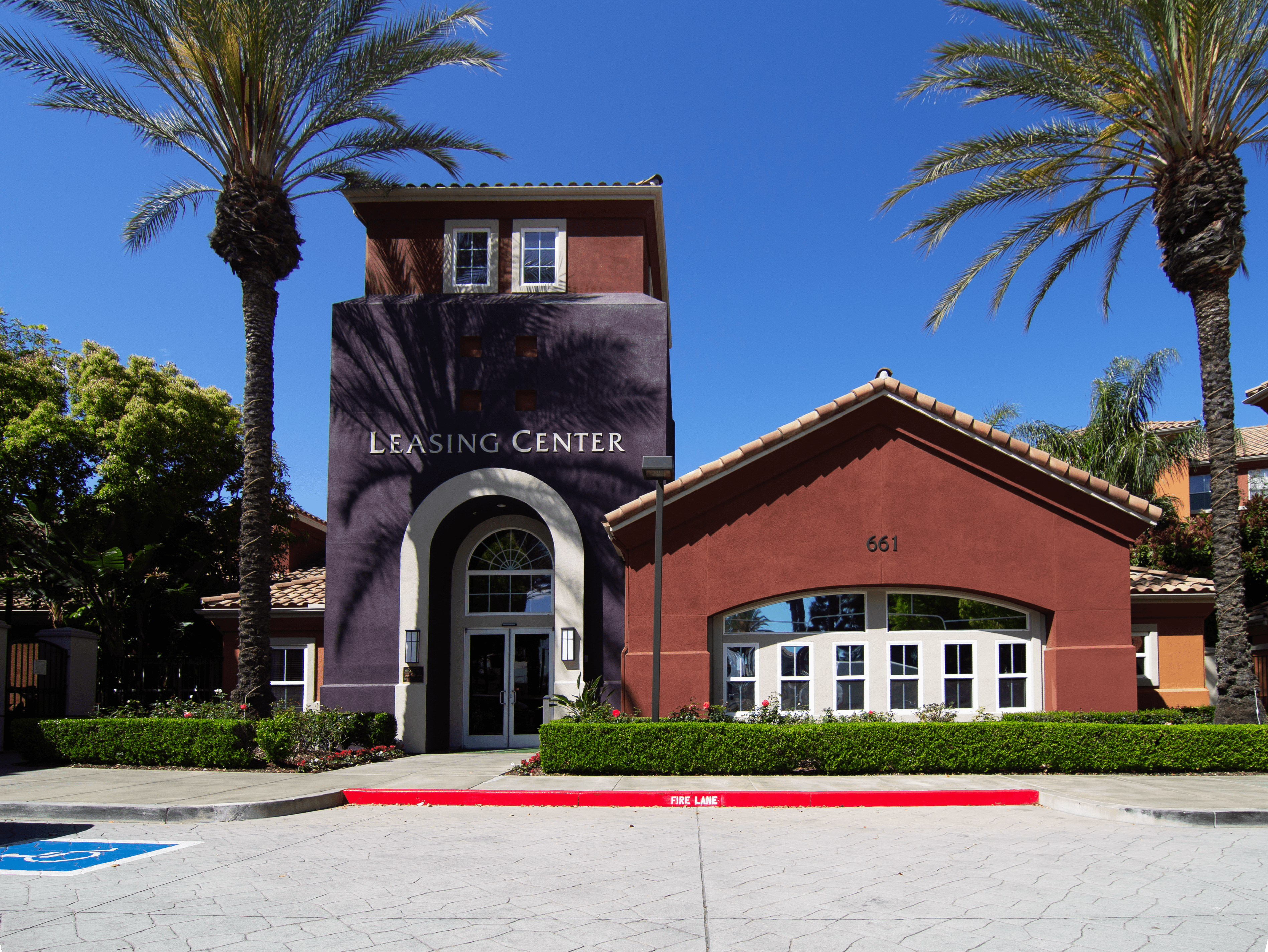 A Leasing Center with a red brick building and palm trees in front.