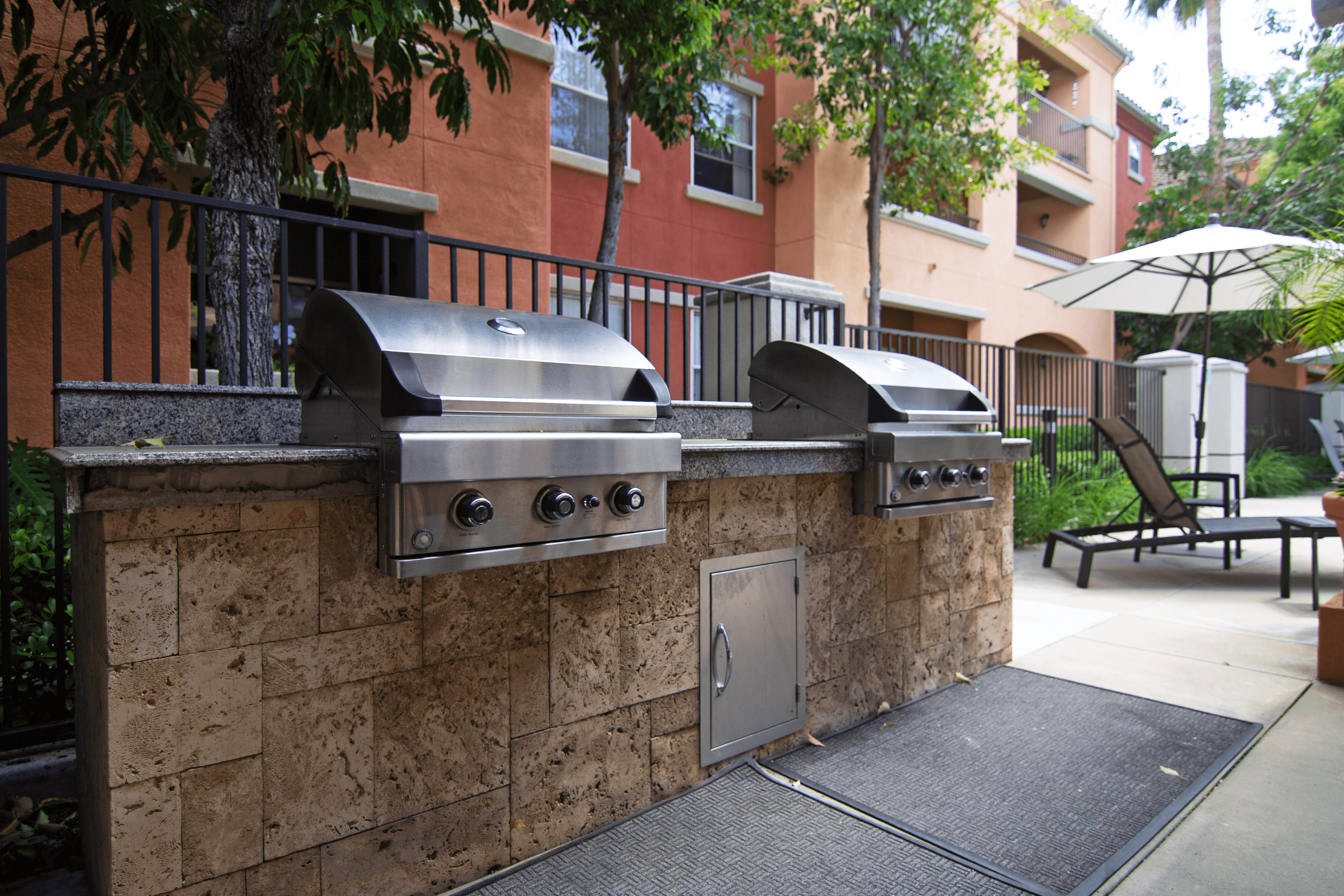 A wall of outdoor grills is in front of a building.
