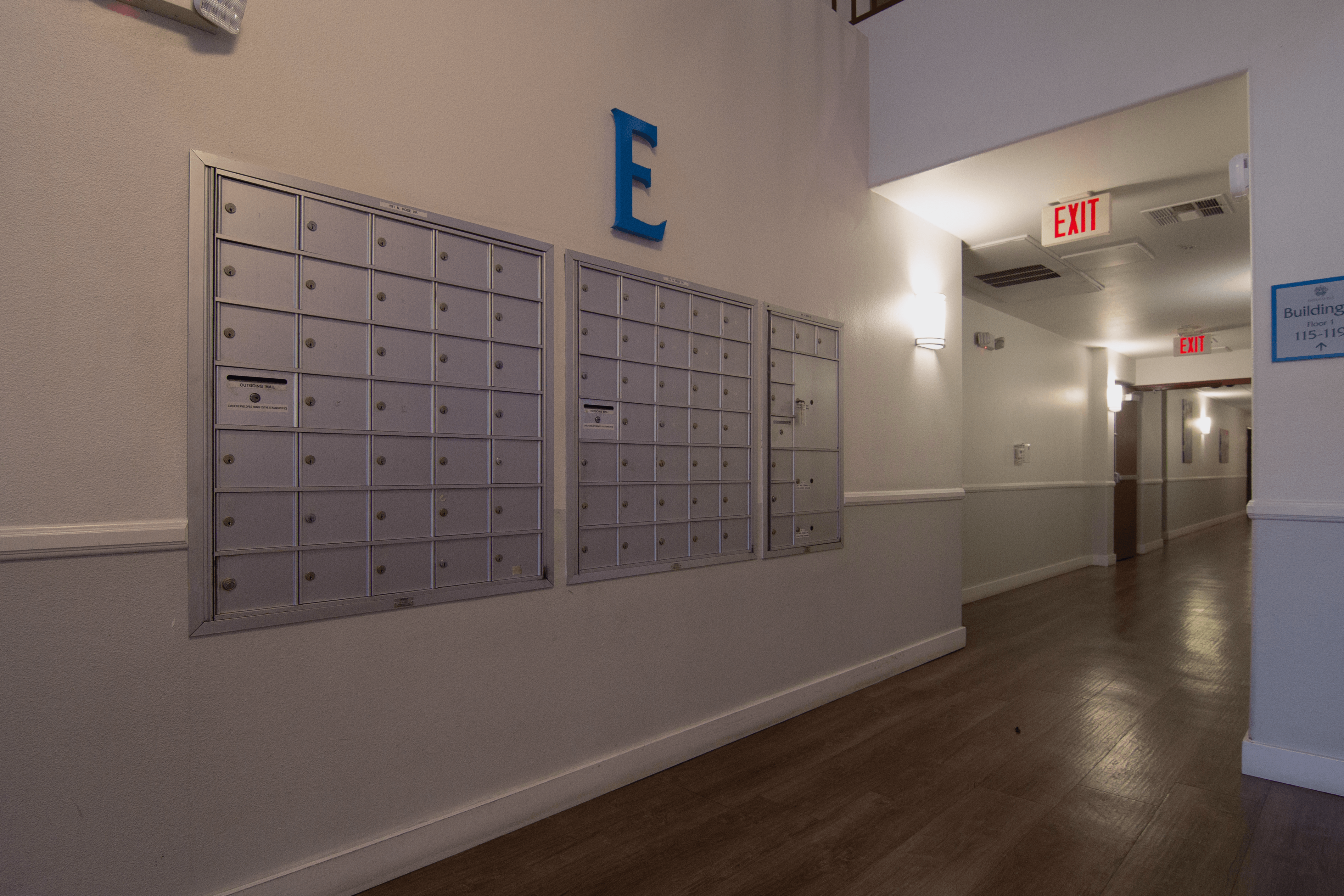 A hallway with a blue letter E on the wall and mailboxes on the wall.