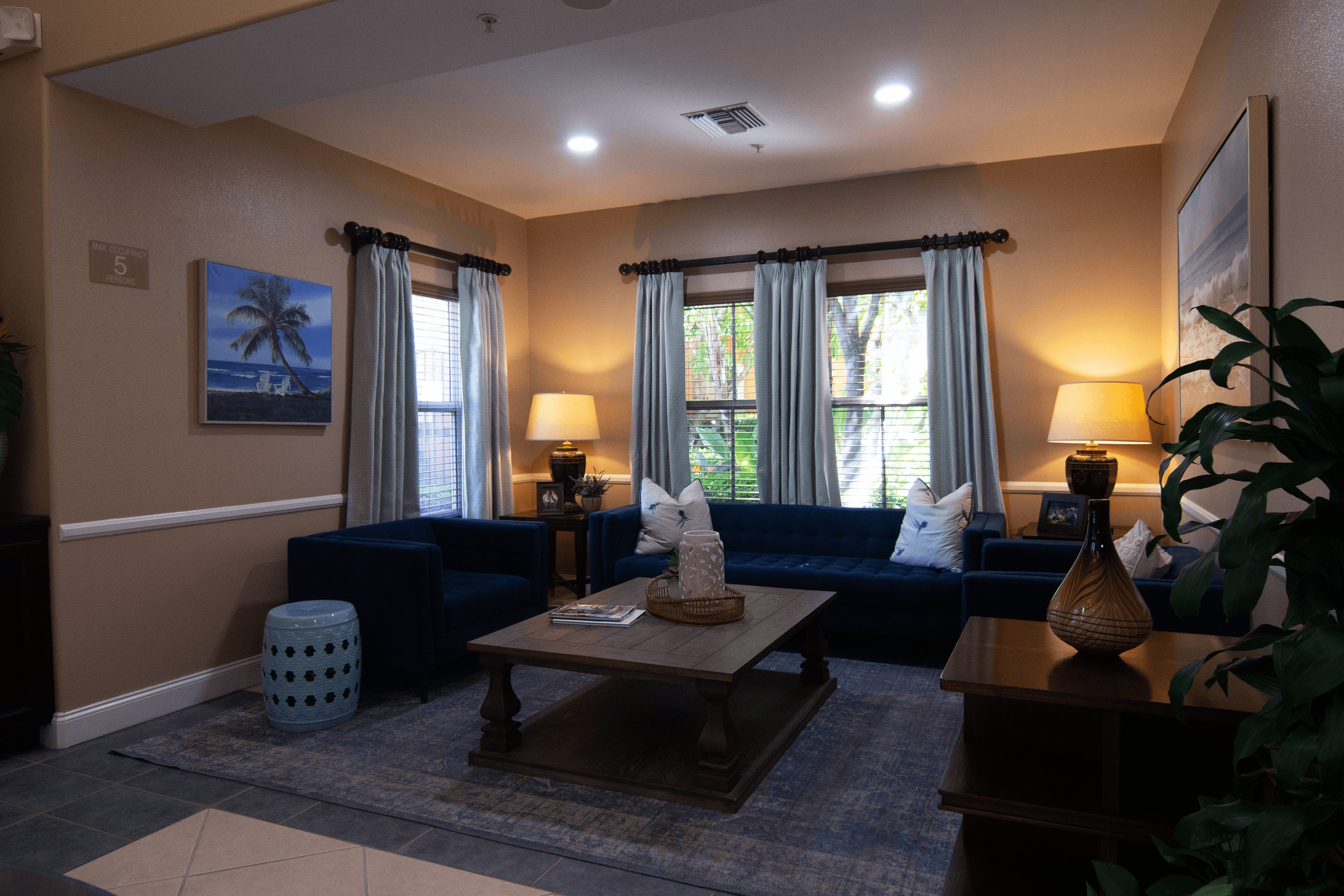 A living room with a blue couch, a wooden coffee table, and a painting of a beach scene on the wall.