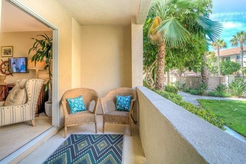 a balcony with two chairs and a view of a palm tree