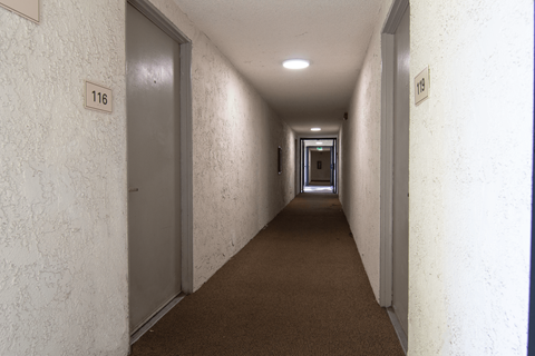 A long hallway with doors on either side and a sign that reads 116.