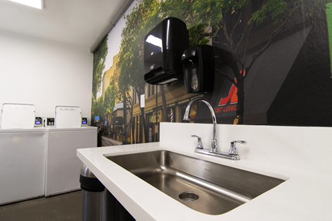 A modern kitchen with a stainless steel sink and a wall-mounted speaker.