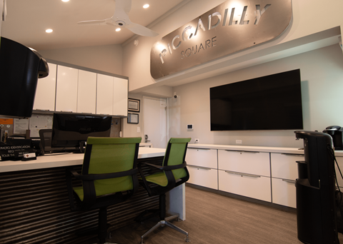 Two green chairs are in front of a white counter with a sign that says 