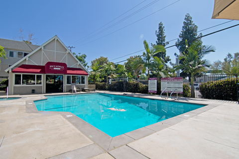 A pool in front of a building with a red awning.