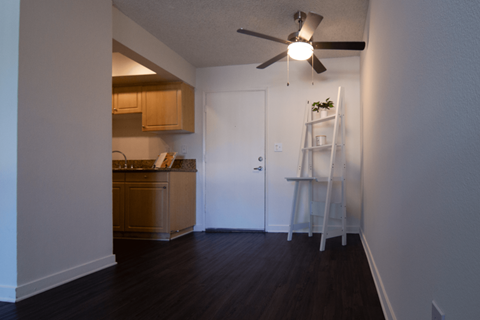 A room with a ceiling fan and a ladder against the wall.