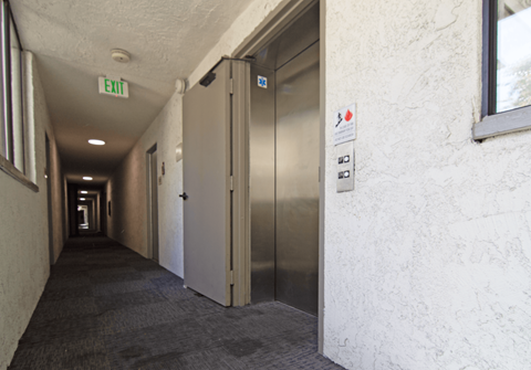 A long hallway with a metal exit sign on the ceiling.