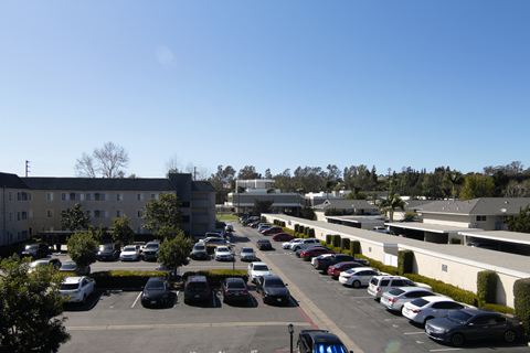 A parking lot with cars and apartment buildings in the background.