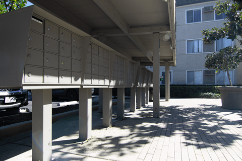 A row of mailboxes are lined up on a sidewalk.