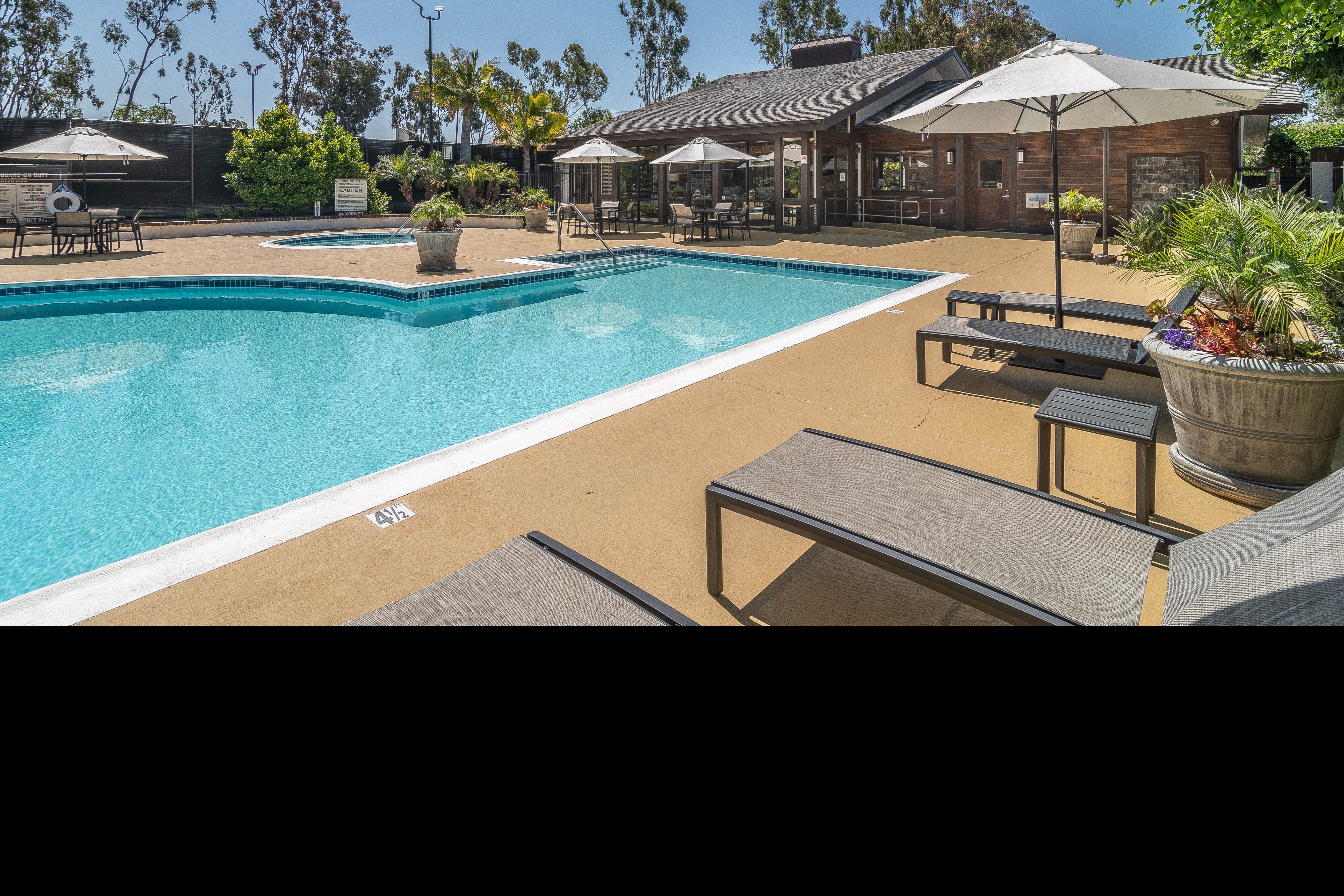 a swimming pool with tables and umbrellas next to a hotel pool