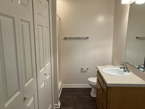 A bathroom with a toilet, sink, and mirror.
