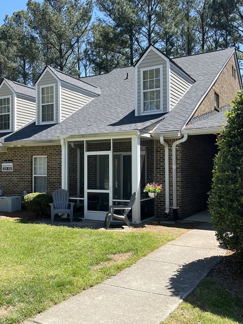 A house with a grey roof and a porch with a chair.