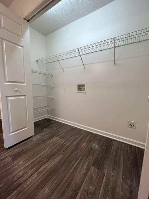 A white door is on the left of a room with a shelf and a light switch.