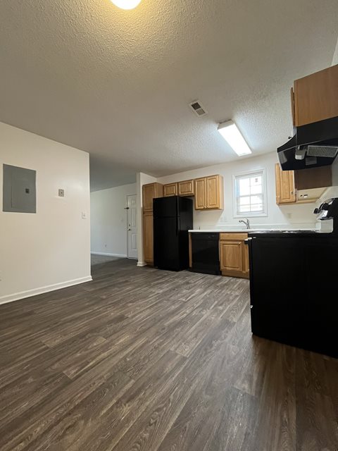 A kitchen with black appliances and wooden cabinets.