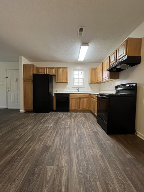 A kitchen with black appliances and wooden cabinets.