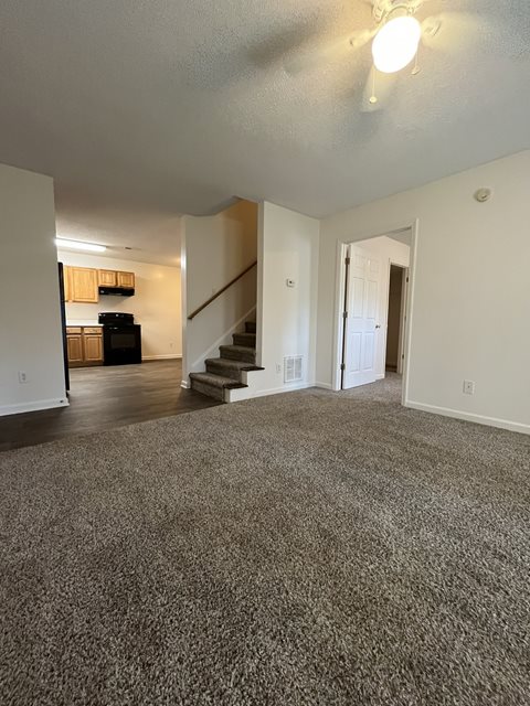 A spacious living room with a staircase leading to the upper floor.