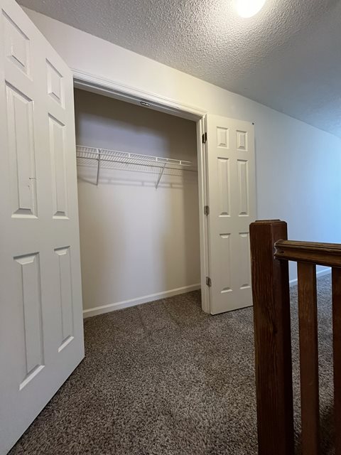 A white door is open to a hallway with a carpeted floor.