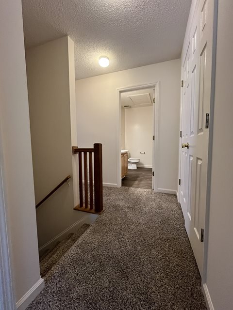 A hallway with a carpeted floor and white walls.