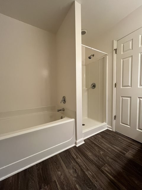 A white bathroom with a bathtub and a door.
