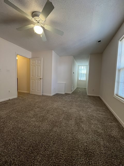 A room with a ceiling fan and carpeted floor.