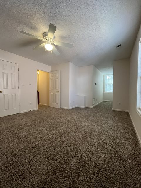 A room with a ceiling fan and carpeted floor.