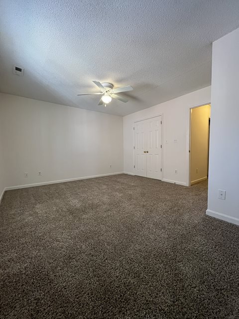 A room with a ceiling fan and carpeted floor.