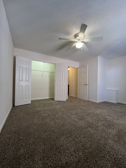 A room with a ceiling fan and carpeted floor.
