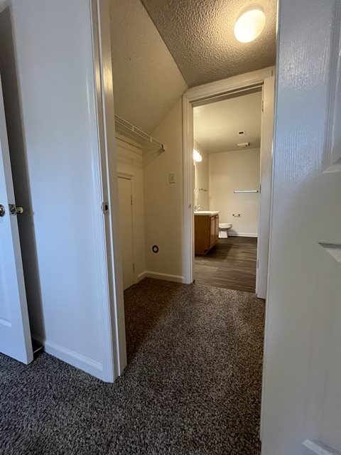 A hallway with a carpeted floor and white walls.