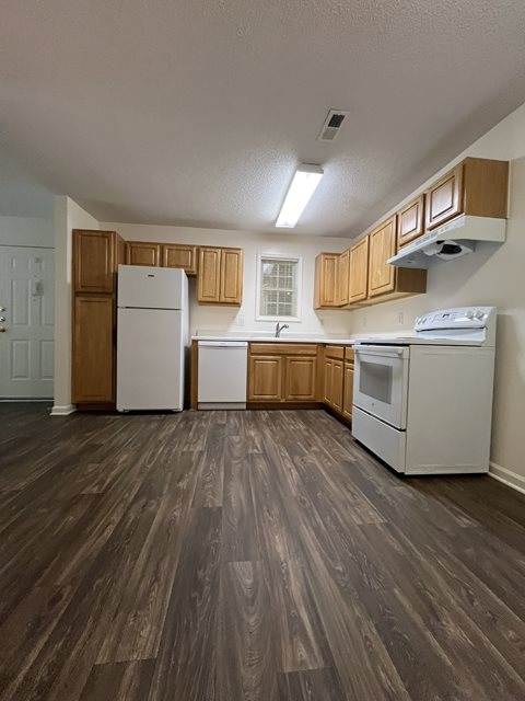 A kitchen with white appliances and wooden cabinets.