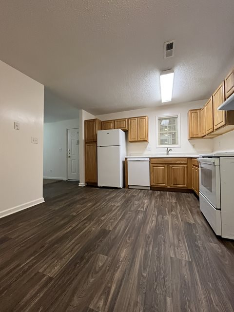 A kitchen with white appliances and wooden cabinets.