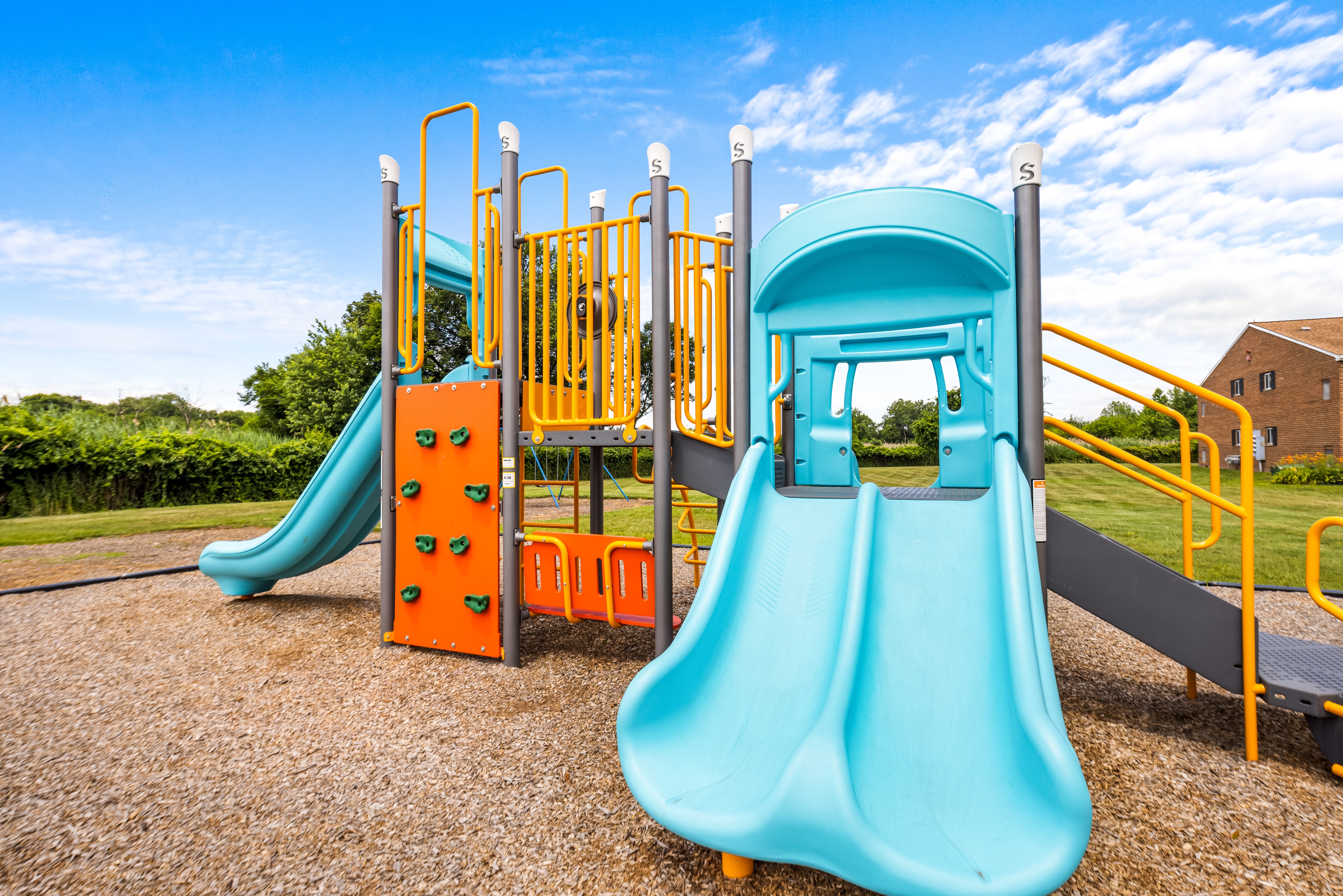 A playground with a blue slide and orange climbing wall.