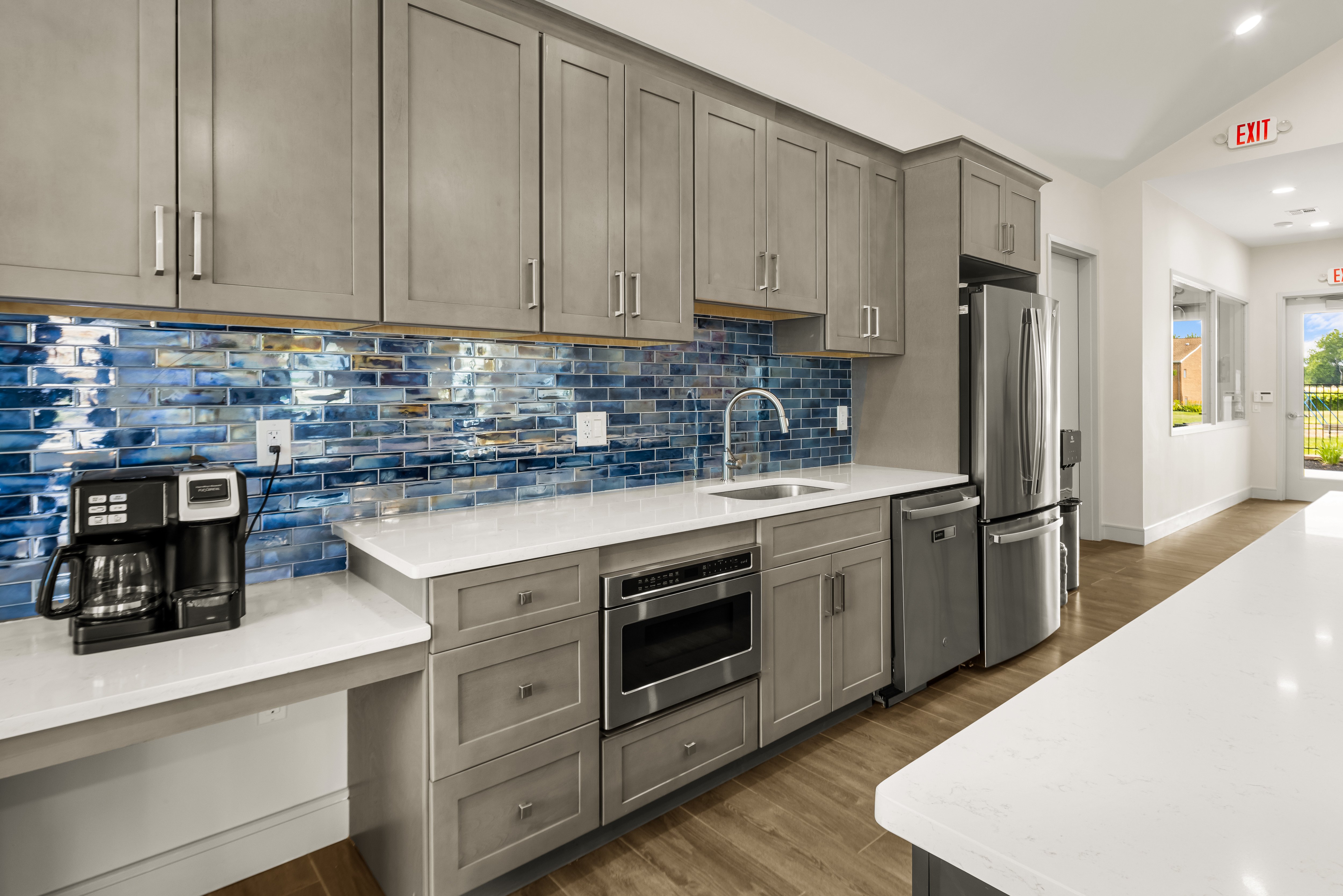 A kitchen with a white counter top and a blue tile backsplash.