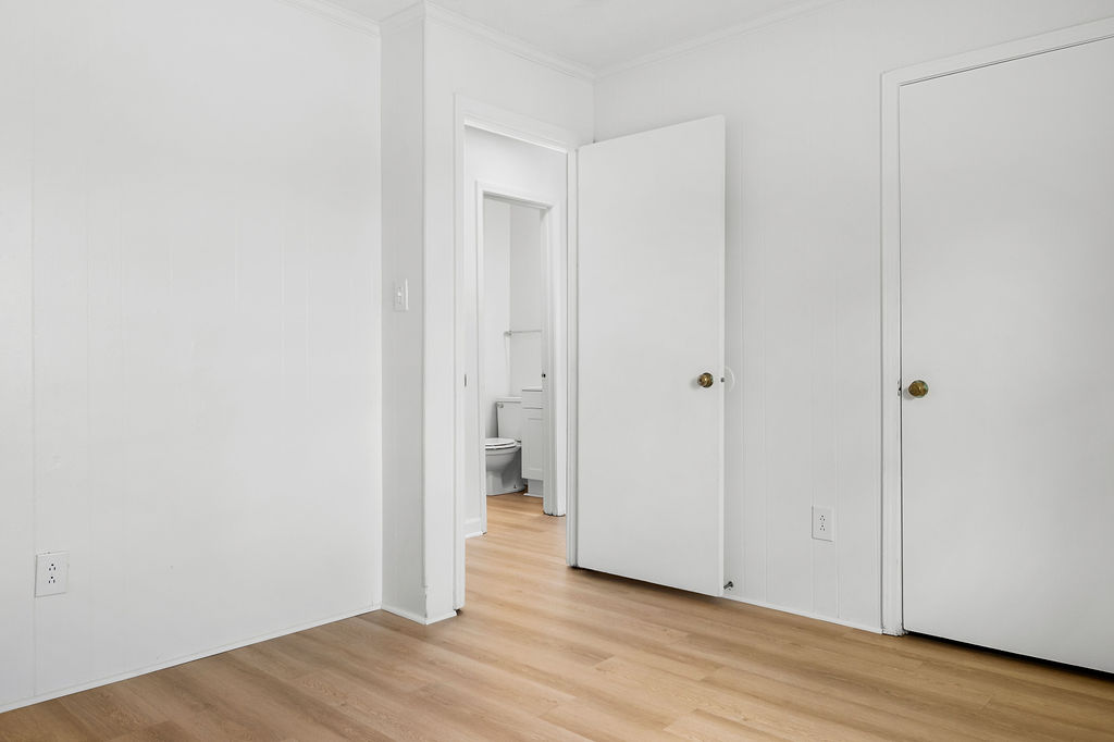 A white room with a doorway leading to a bathroom.