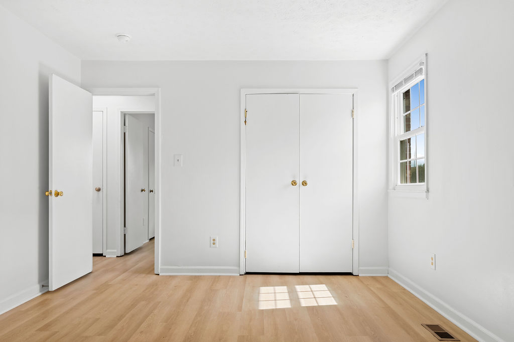 A white room with a wooden floor and three doors.