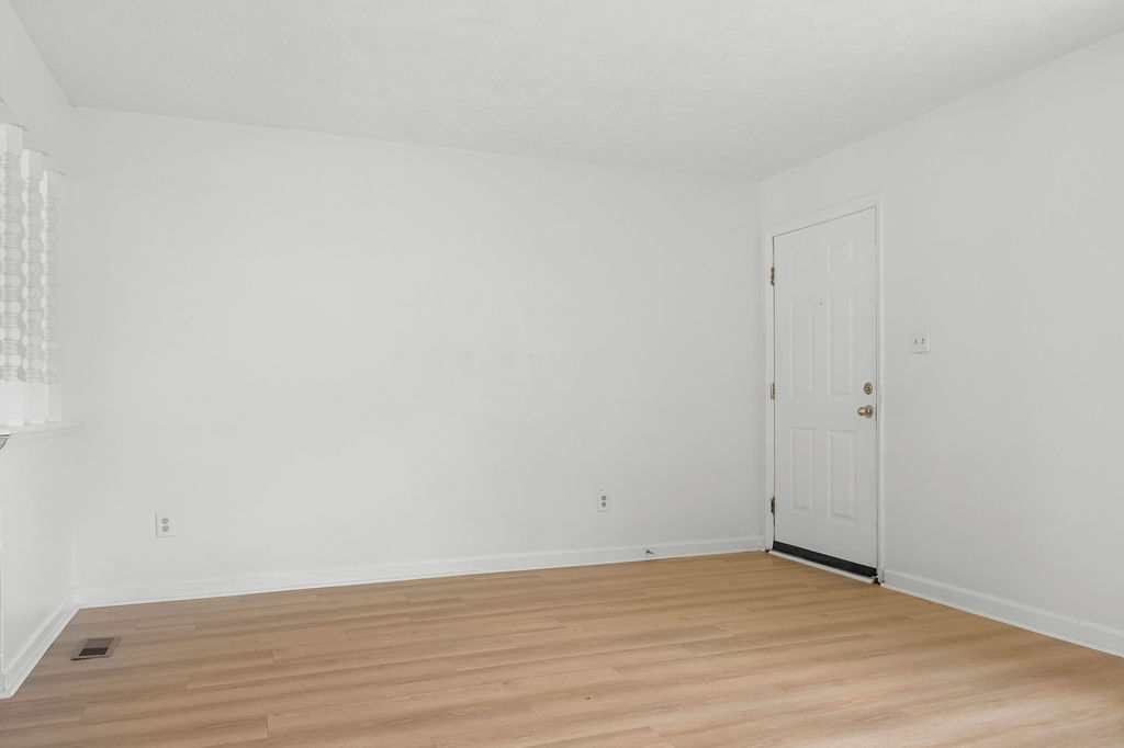 A room with a white door and wooden floor.