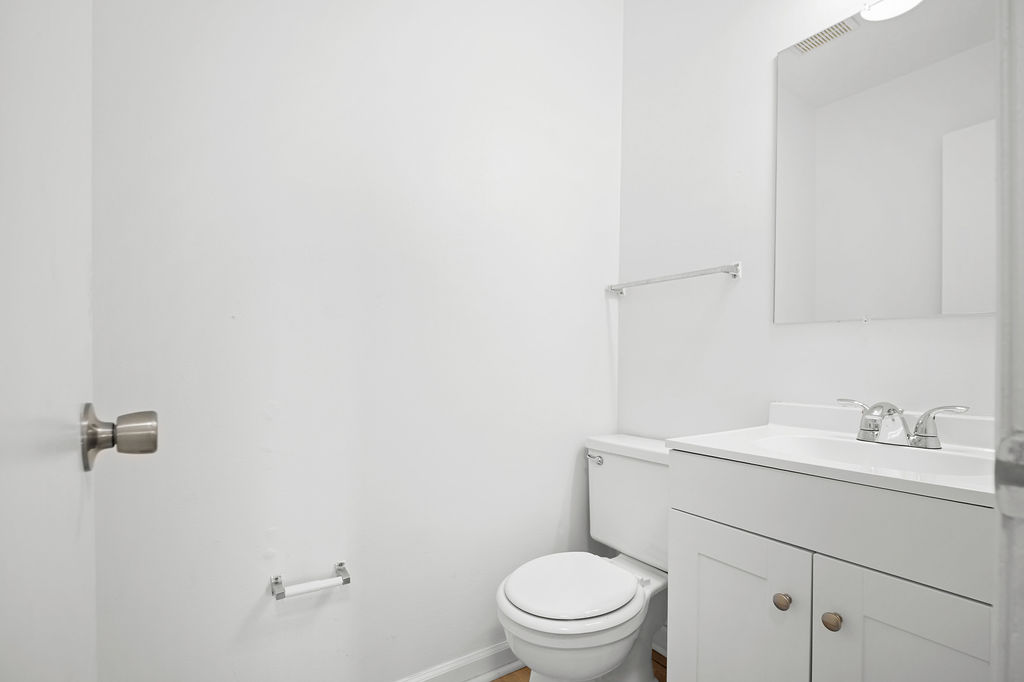 A white bathroom with a toilet, sink, and mirror.
