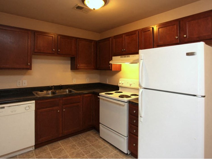 Upgraded kitchen with dark wood cabinets, range, refrigerator, sink, and dishwasher.