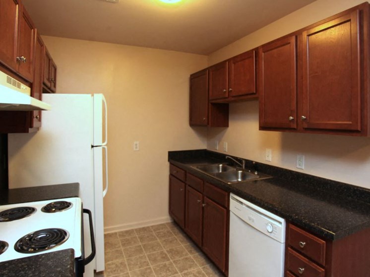 Upgraded kitchen with dark wood cabinets, range, refrigerator, sink, and dishwasher.
