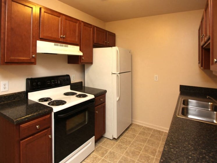 Upgraded kitchen with dark wood cabinets, range, refrigerator, and sink