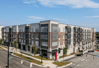 A large building with a red sign on the corner.