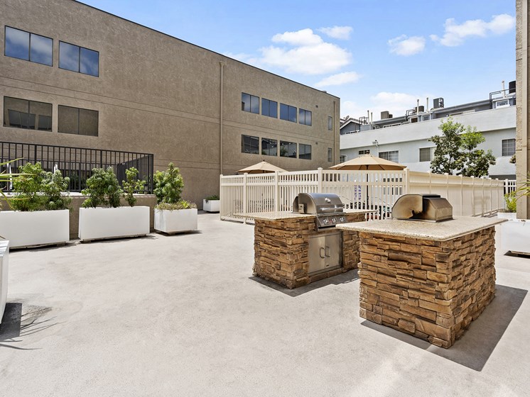North Hollywood Apartments - Community Sun Deck with Two BBQ Grills with Built In Counters and Surrounded by Potted Greenery.