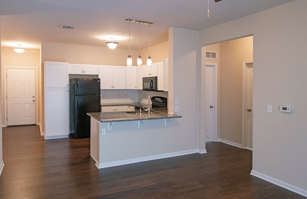 A kitchen with a black refrigerator and white cabinets.