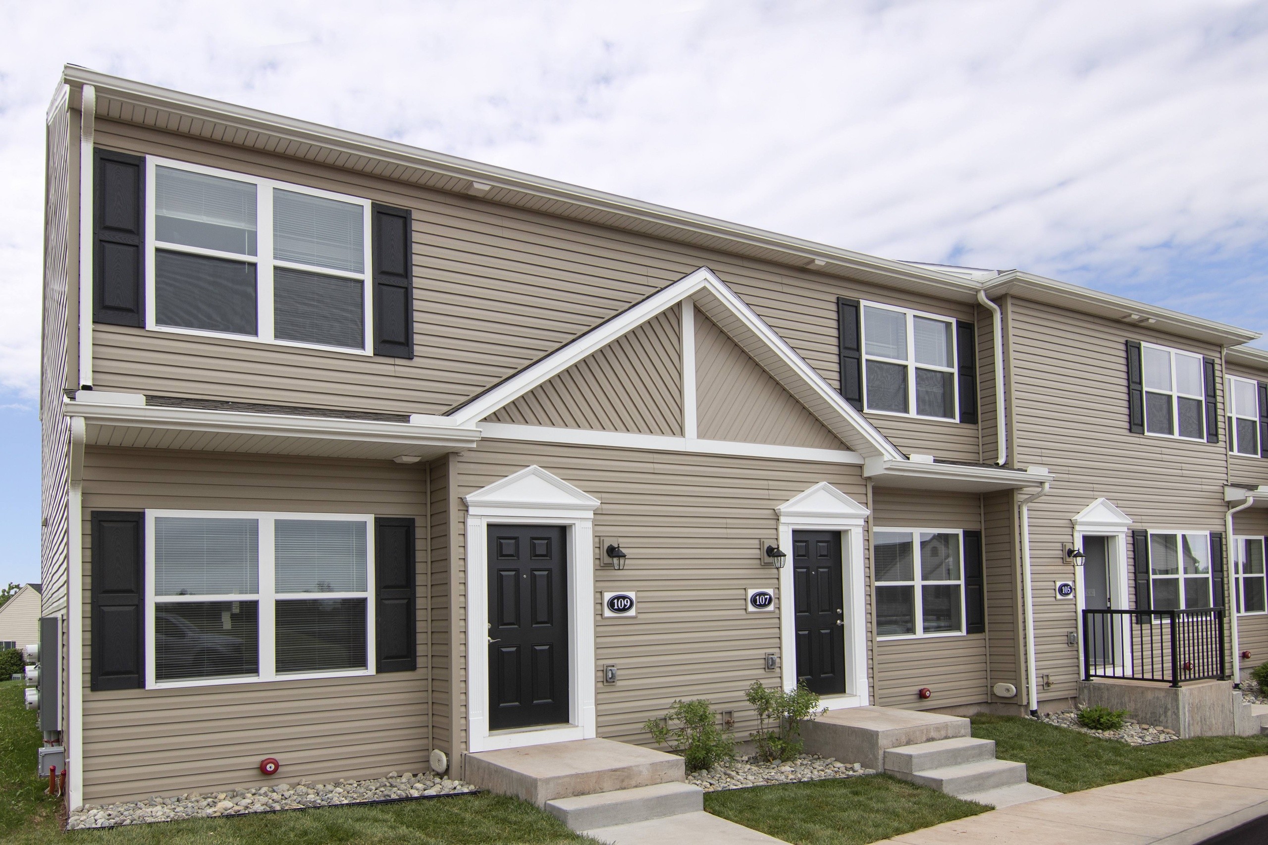 A two-story house with a grey facade and a black front door.