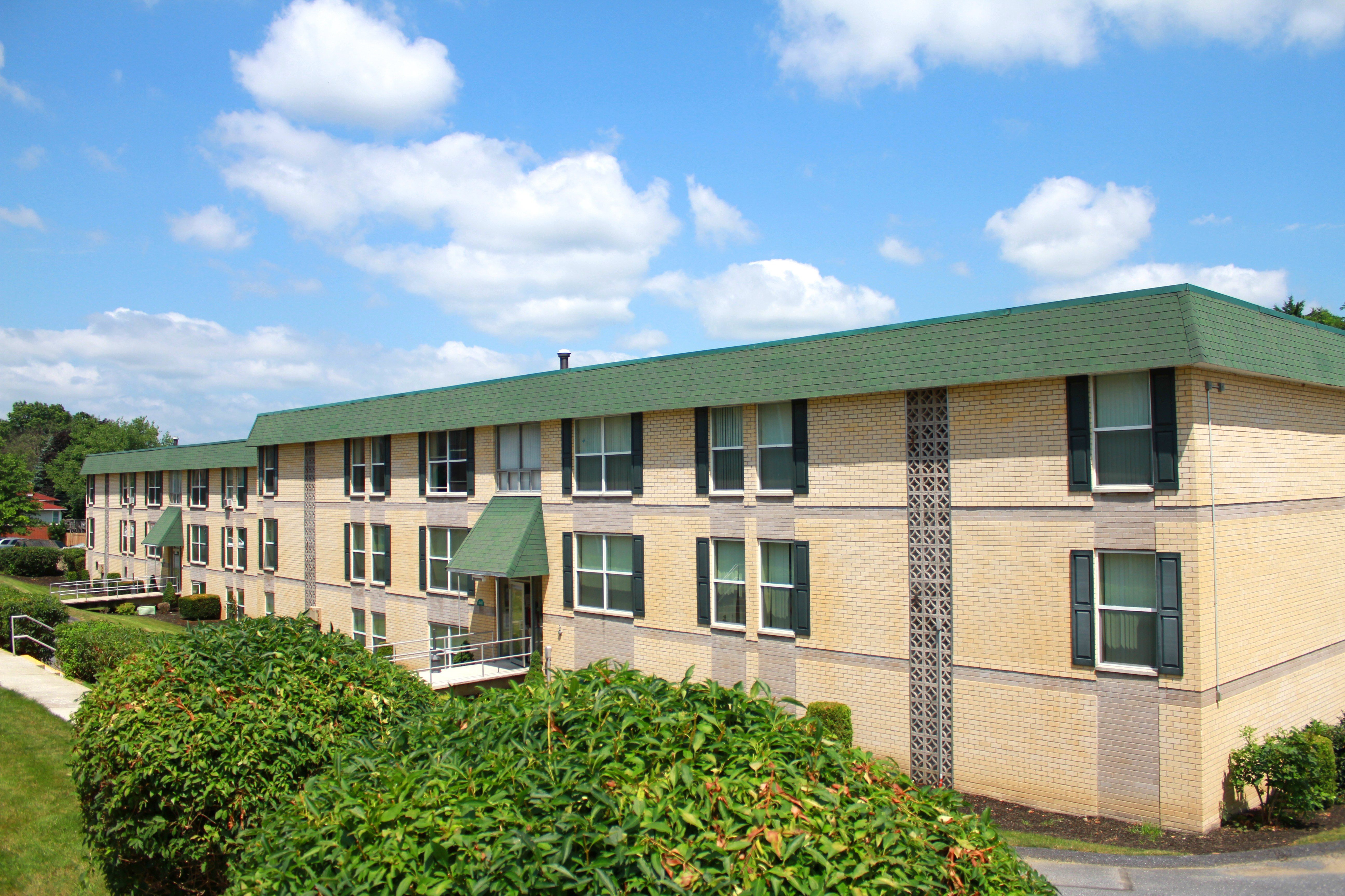 A building with a green roof and a brick facade with a green awning.