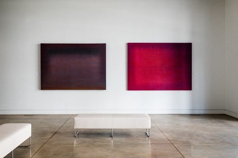 Art gallery featuring two leather benches and two modern paintings