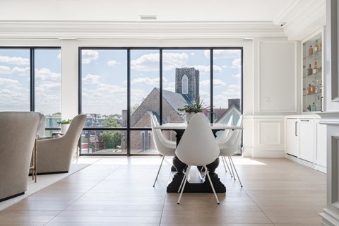 Lounge with modern dining table and chairs, bar and view of city out windows.
