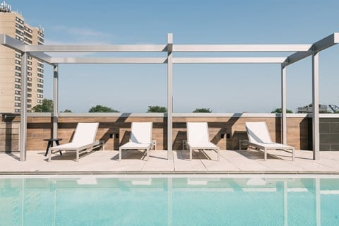 Pool deck with lounge chairs and view of sky and city