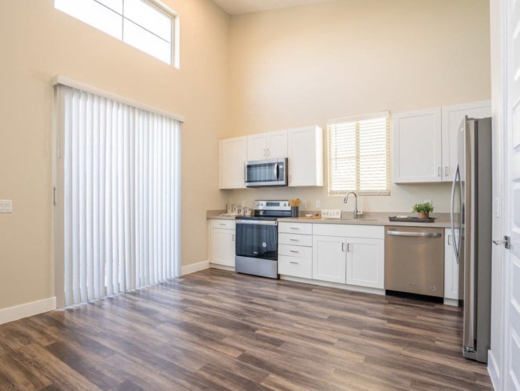 Model kitchen at Village Green of Queen Creek with wood-style flooring, modern appliances and a sliding glass door
