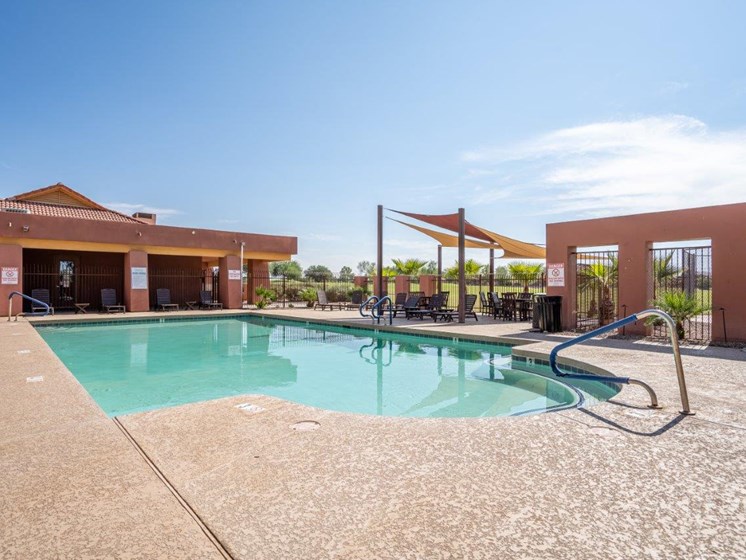 The pool is surrounded by a sundeck with lounge chairs at Village Greens of Queen Creek